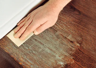 wood floor maintenance - a Floors Doctor operative sands the edges of a wooden floor